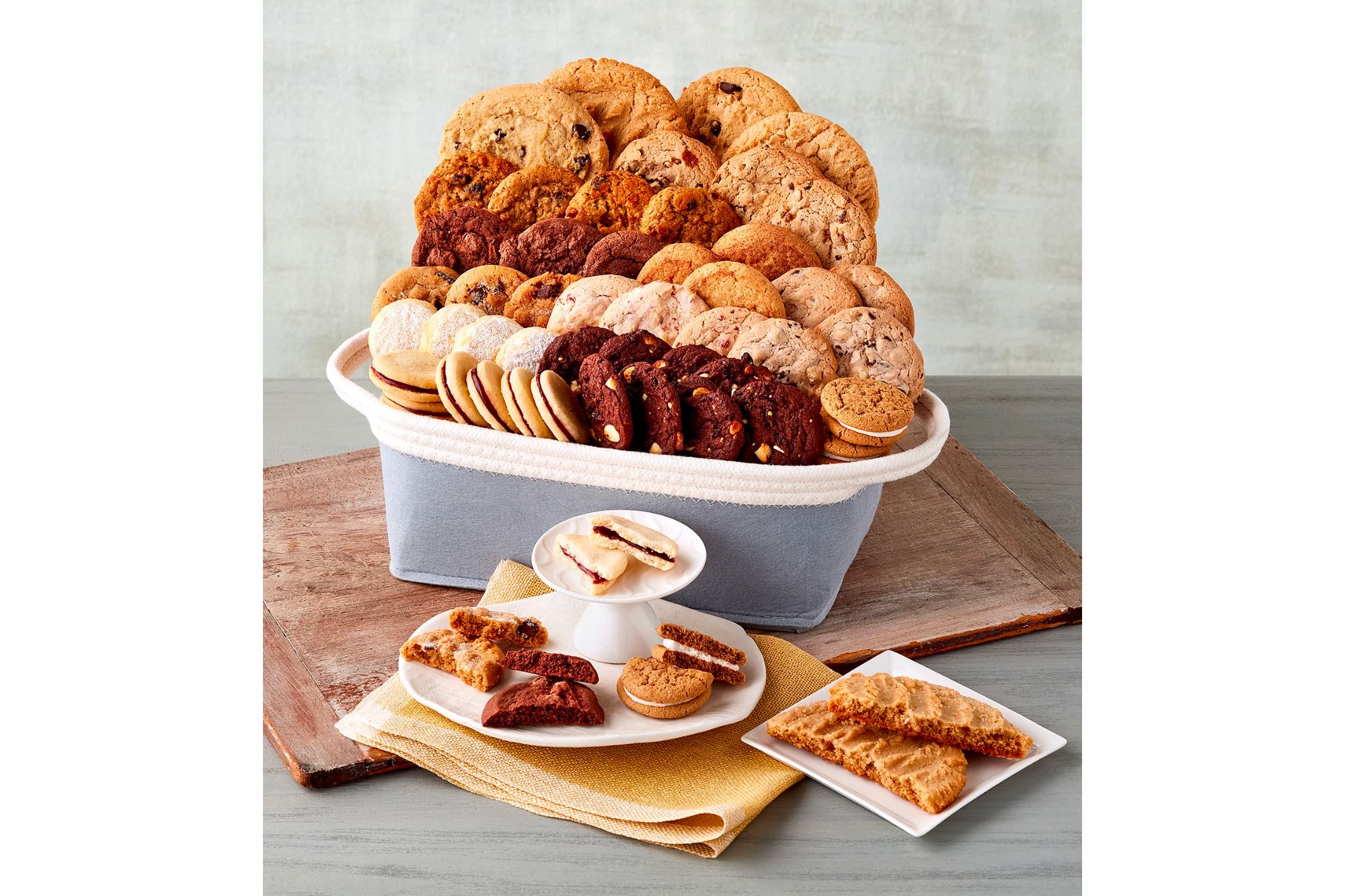 An assortment of cookies in a basket and cookies on a plate.