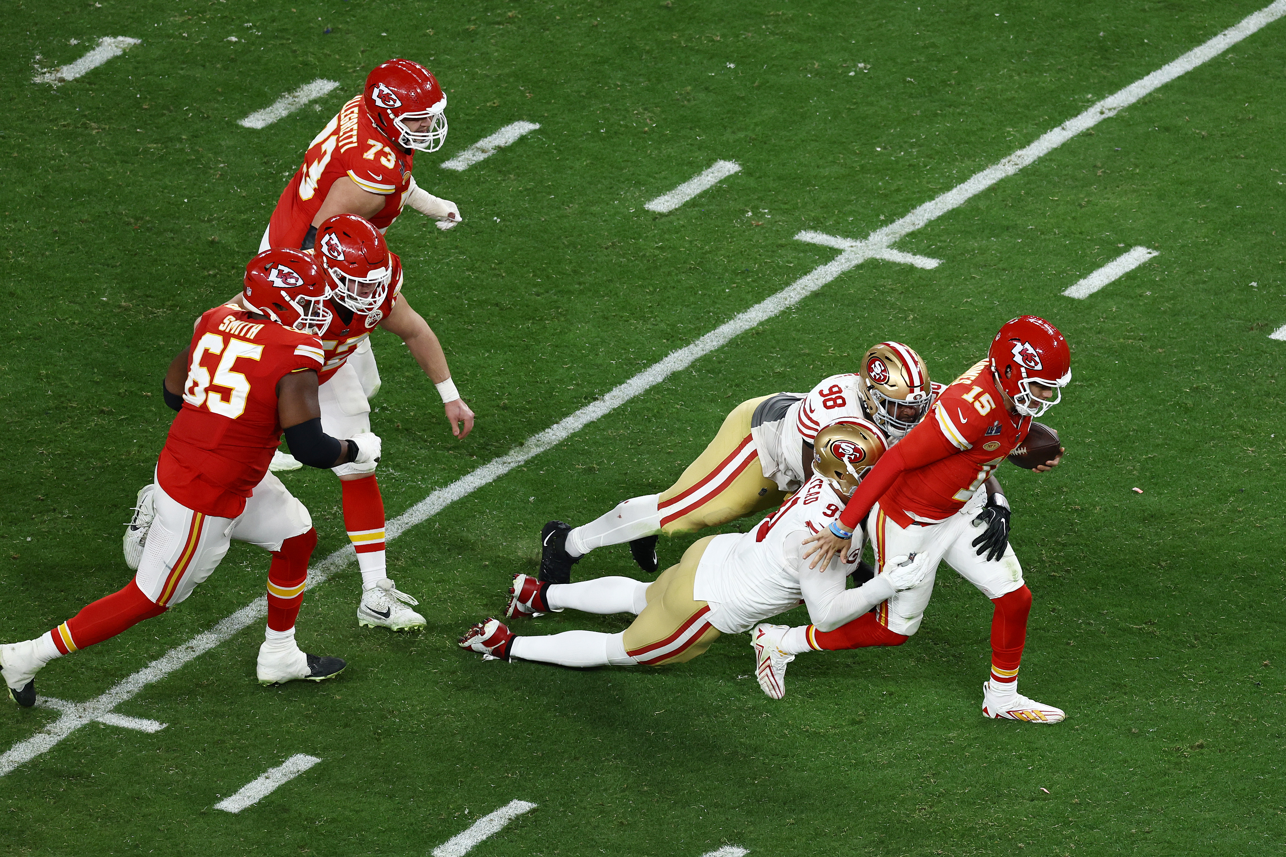 Patrick Mahomes #15 of the Kansas City Chiefs tries to avoid being tackled by Arik Armstead #91 and Javon Hargrave #98 of the San Francisco 49ers