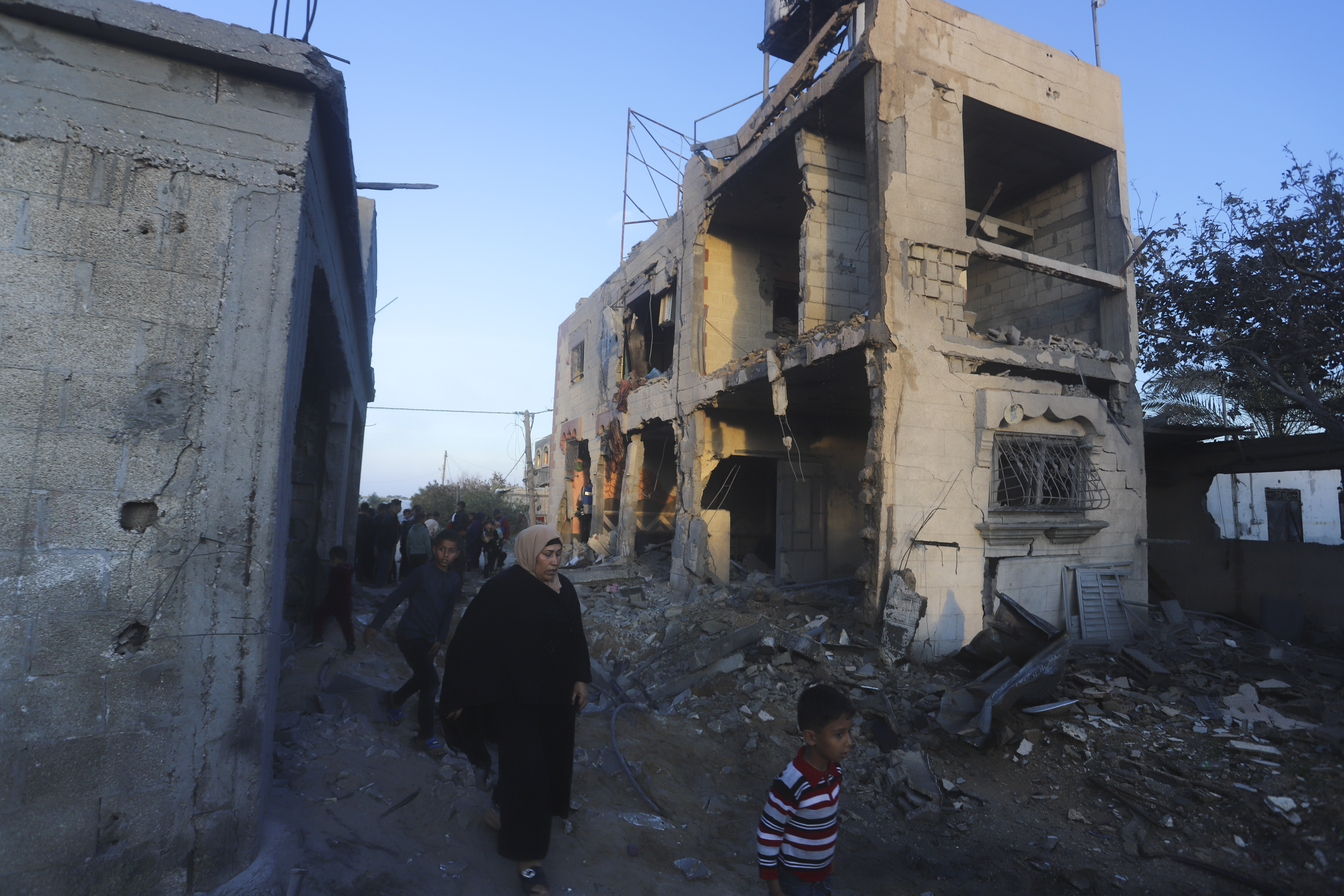 Palestinians walk by a residential building destroyed in an Israeli strike in Rafah, Gaza Strip, on Feb. 11, 2024. 