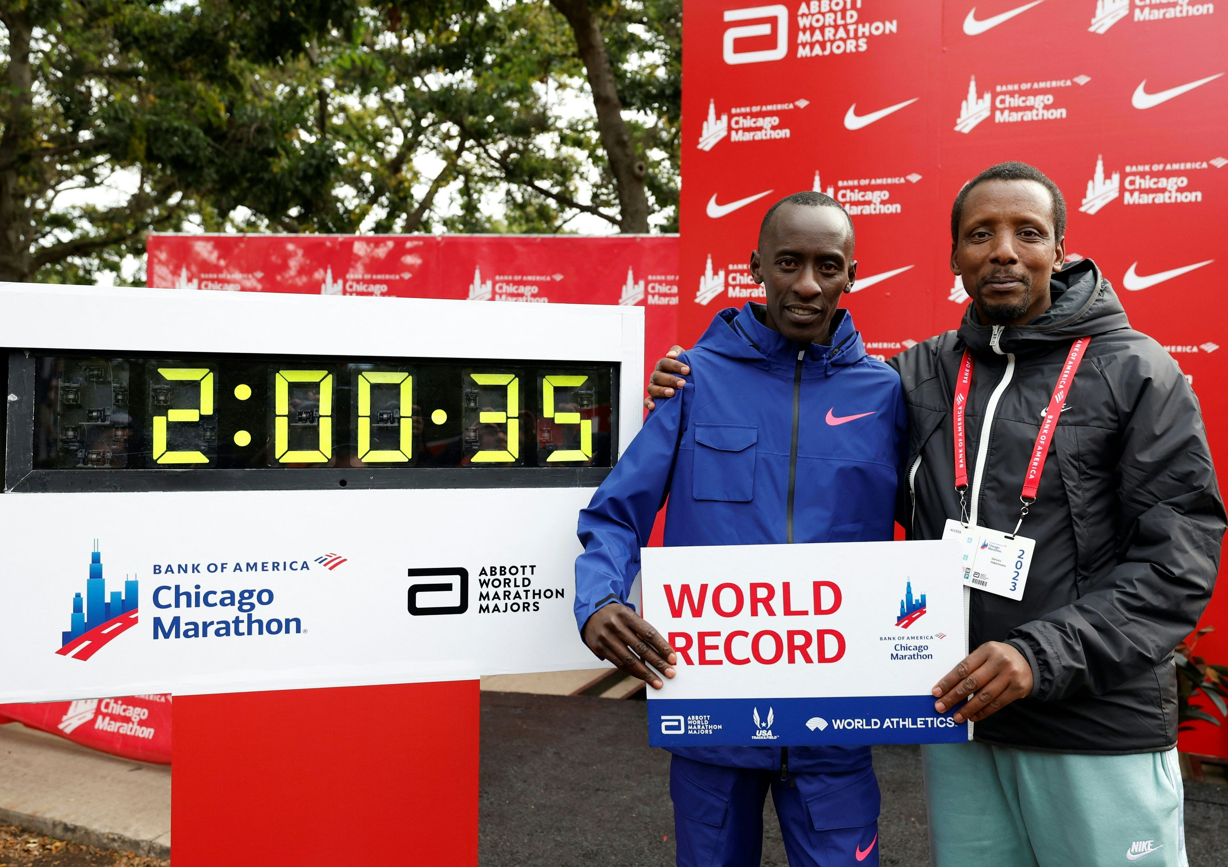 Kelvin Kiptum poses with his coach Gervais Hakizimana (right) next to the clock marking Kiptum's time after winning the 2023 Bank of America Chicago Marathon in Chicago, Illinois on Oct. 8, 2023. 