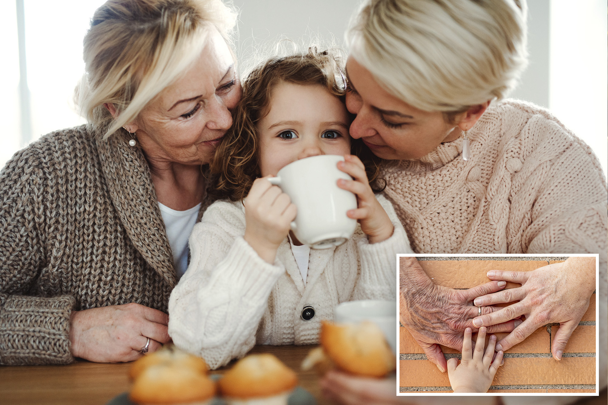 A happy small girl with her mother and grandmother sitting at a table at home, drinking from a mug.