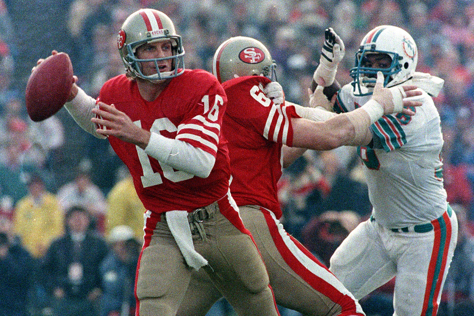 San Francisco 49ers quarterback Joe Montana (16) looks for a receiver behind protective blocking of left guard John Ayers (68) against Miami Dolphins' Don McNeal during the first half of NFL football's Super Bowl XIX in Palo Alto, Calif. 