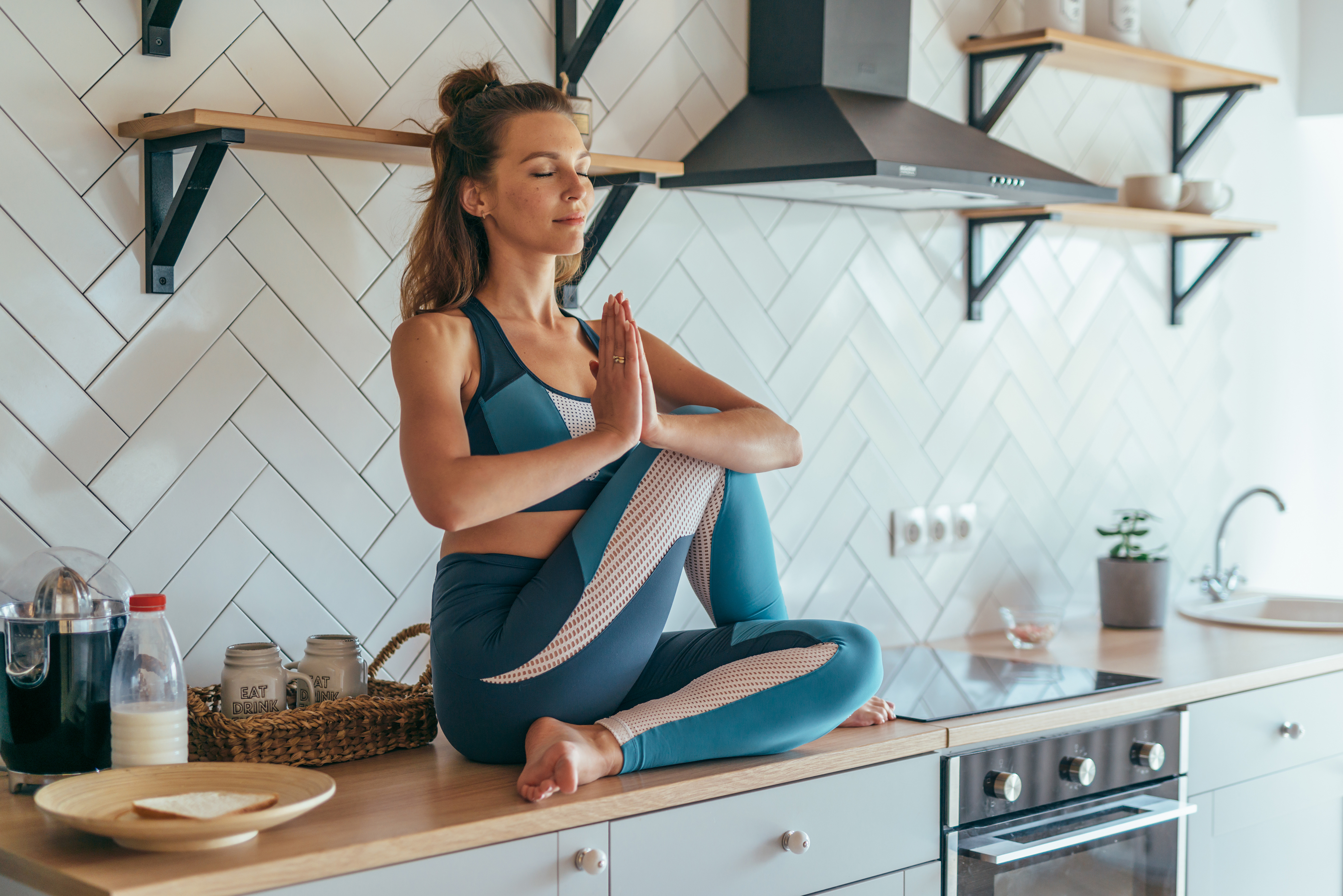 Fit woman meditating on kitchen table